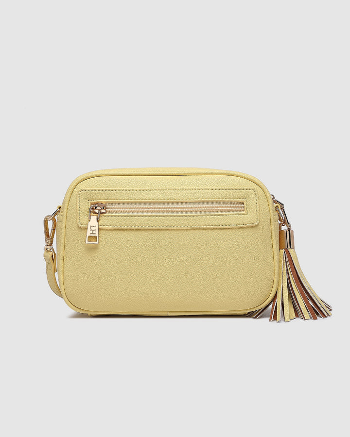 Yellow crossbody bag with a tassel on a light gray background